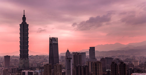 Modern buildings in city against sky during sunset