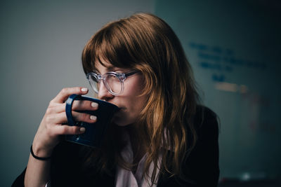 Young businesswoman drinking coffee at creative office