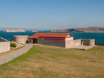 Buildings by sea against clear sky