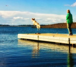 Man with dog by sea against sky