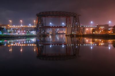 Illuminated bridge over canal against sky at night