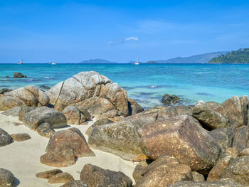 Rocks on beach against blue sky