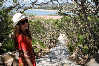 Side view of woman in sunglasses amidst trees on steps