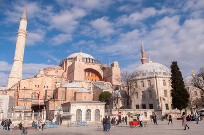 Group of people in front of historic building against sky