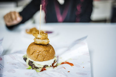 Close-up of hamburger served on table against person