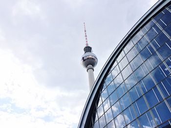 Low angle view of fernsehturm against cloudy sky