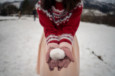 Midsection of woman holding snowball while standing outdoors