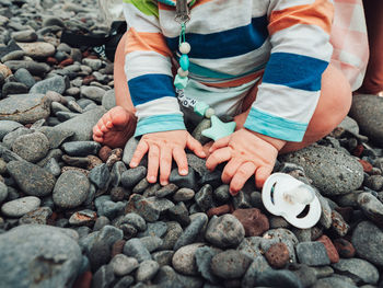 Low section of child sitting on pebbles