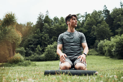 Young man doing exercises outside on grass during his calisthenics workout