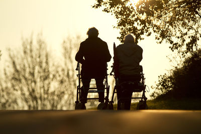 Rear view of men walking against trees