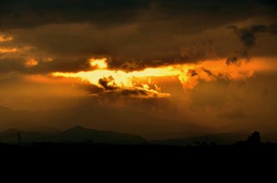 Silhouette of mountain range against dramatic sky