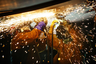 Mechanics welding airplane wing at industry during night