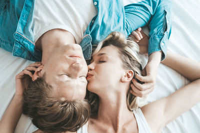High angle view of couple embracing while lying on bed