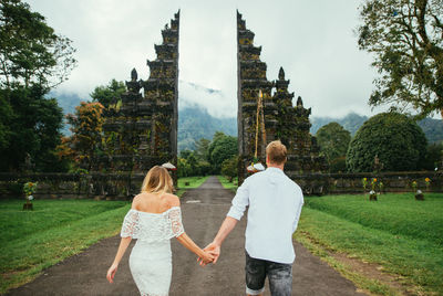 Couple walking on footpath at gate against sky