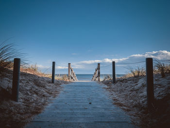 Wooden posts on beach against sky