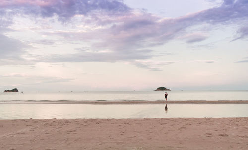 Man standing on beach against sky during sunset