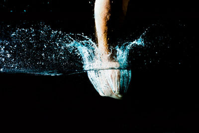 Human hand splashing water against black background