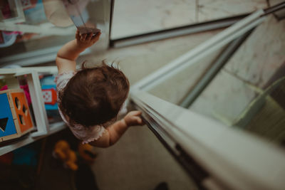 High angle view of baby girl standing by window at home