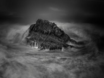 Rocks on the shoreline on a stormy and dark afternoon, moving waves