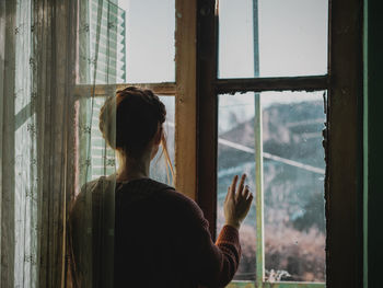 Rear view of woman looking through window