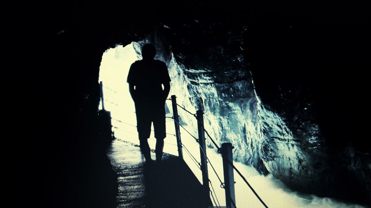 tunnel, real people, silhouette, architecture, lifestyles, people, full length, nature, men, walking, the way forward, rear view, leisure activity, standing, built structure, outdoors, direction, day, dark, light at the end of the tunnel, underpass