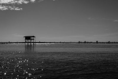 Stilt house in sea against sky