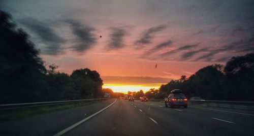 Cars on road against sky during sunset