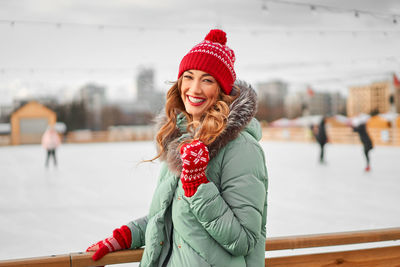 Portrait of smiling young woman wearing knit hat standing outdoors