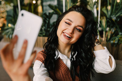 Portrait of smiling young woman using smart phone outdoors