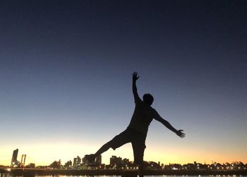 Silhouette man with arms outstretched against sky during sunset