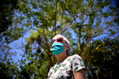 Low angle view of man wearing sunglasses against trees