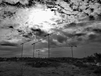 Fence on landscape against storm clouds