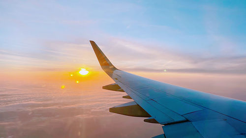 Airplane wing against sky during sunset