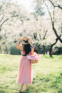 Full length of woman standing by pink flowers on field