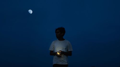 Low angle view of man standing against blue sky