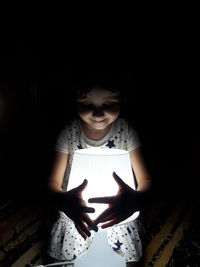 Girl holding smart phone while standing in the dark