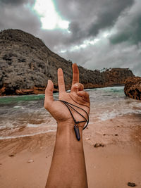 Midsection of person on beach against sky