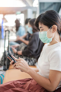 Woman wearing mask using phone at airport