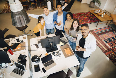 High angle portrait of computer programmers standing by desk in office