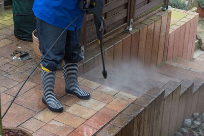 Low section of man cleaning paving stones