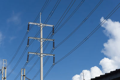 Low angle view of electricity pylon against blue sky