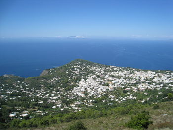 High angle view of townscape by sea against blue sky