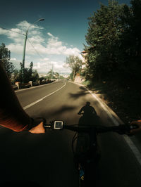 Man riding bicycle on road against sky