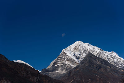 Low angle view of snowcapped mountain against blue sky