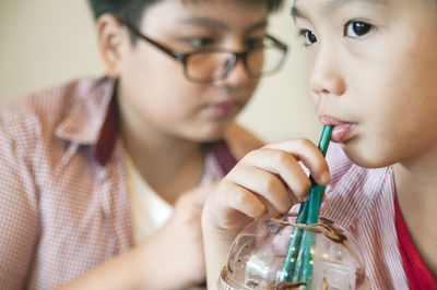 Close-up of boy drinking drink with straw