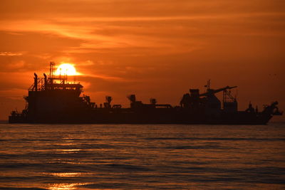 Silhouette ship in sea against sky during sunset