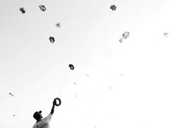 Low angle view of man flying kite against clear sky