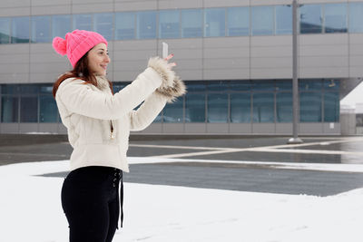 Woman wearing hat standing against building