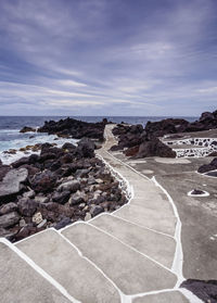 Scenic view of rocks by sea against sky