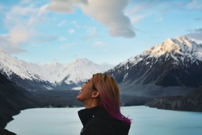 Woman standing on snowcapped mountain against sky